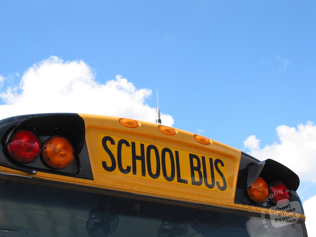 The top of a school bus against a blue sky.